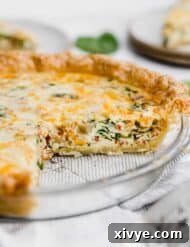 Spinach and Bacon Quiche or quiche Lorraine in a pie plate on a white background.