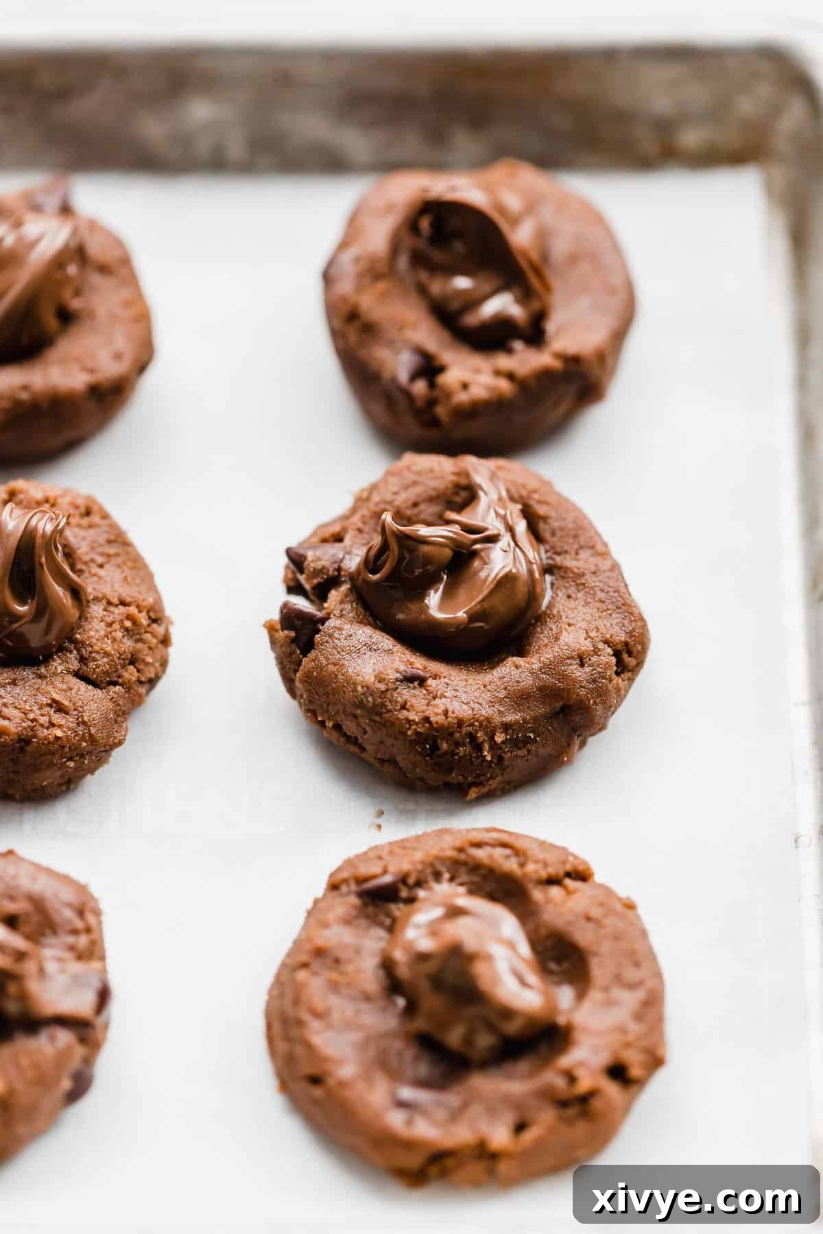 A spoonful of Nutella placed in the center of raw Nutella cookie dough balls with an indentation.