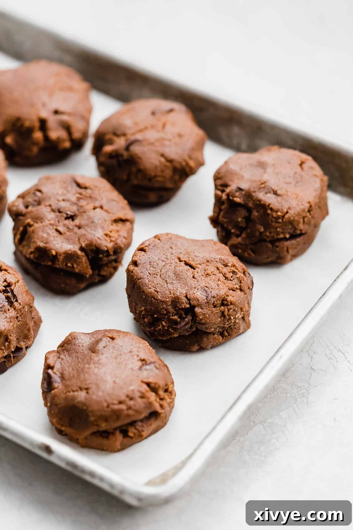 Nutella stuffed cookie dough balls neatly arranged on a baking sheet, ready for the oven.