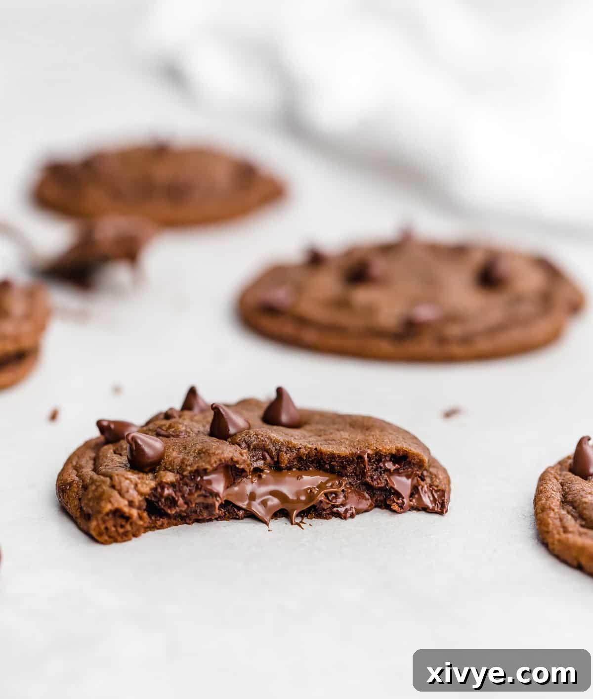 A Nutella Stuffed Nutella Cookie cut in half showing the warm, melted Nutella in the center of the cookie.