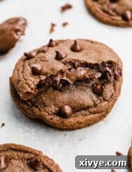 A Nutella Stuffed Nutella Cookie cut in half showing Nutella coming from the center of the cookie.