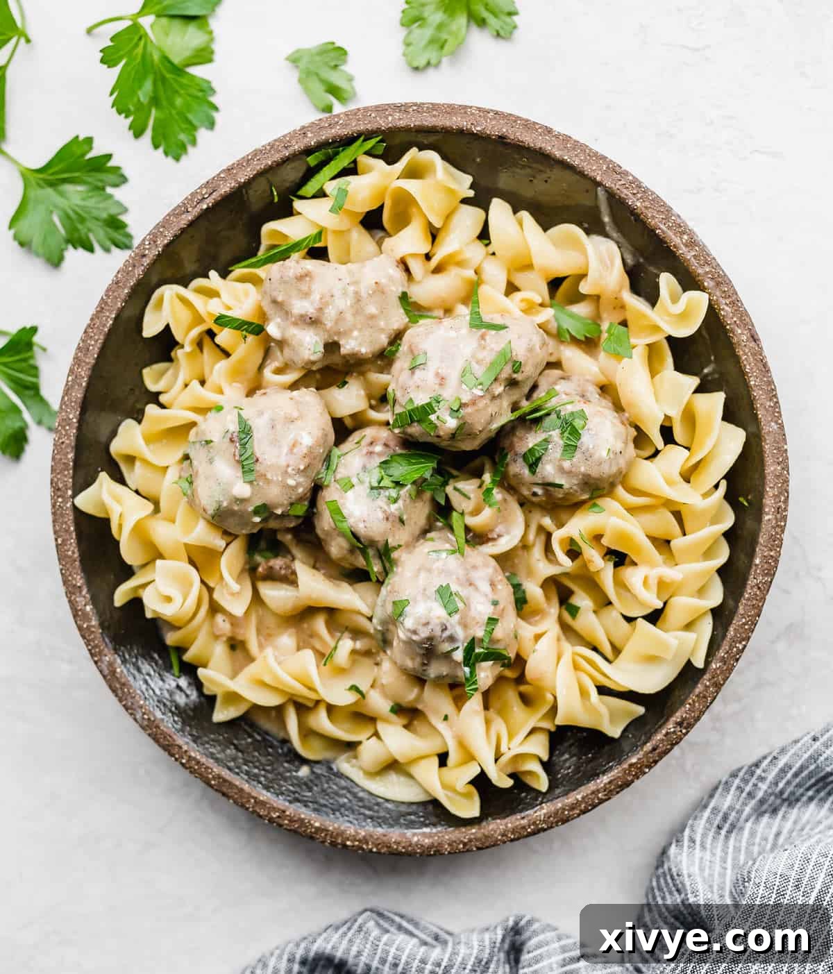 Swedish Meatballs on a bed of cooked egg noodles in a black plate.