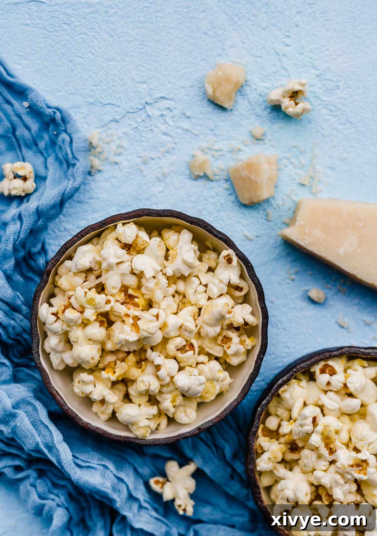 Gourmet Parmesan Popcorn 2 Parmesan Popcorn in a black rimmed bowl on a light blue background, showcasing its cheesy coating.