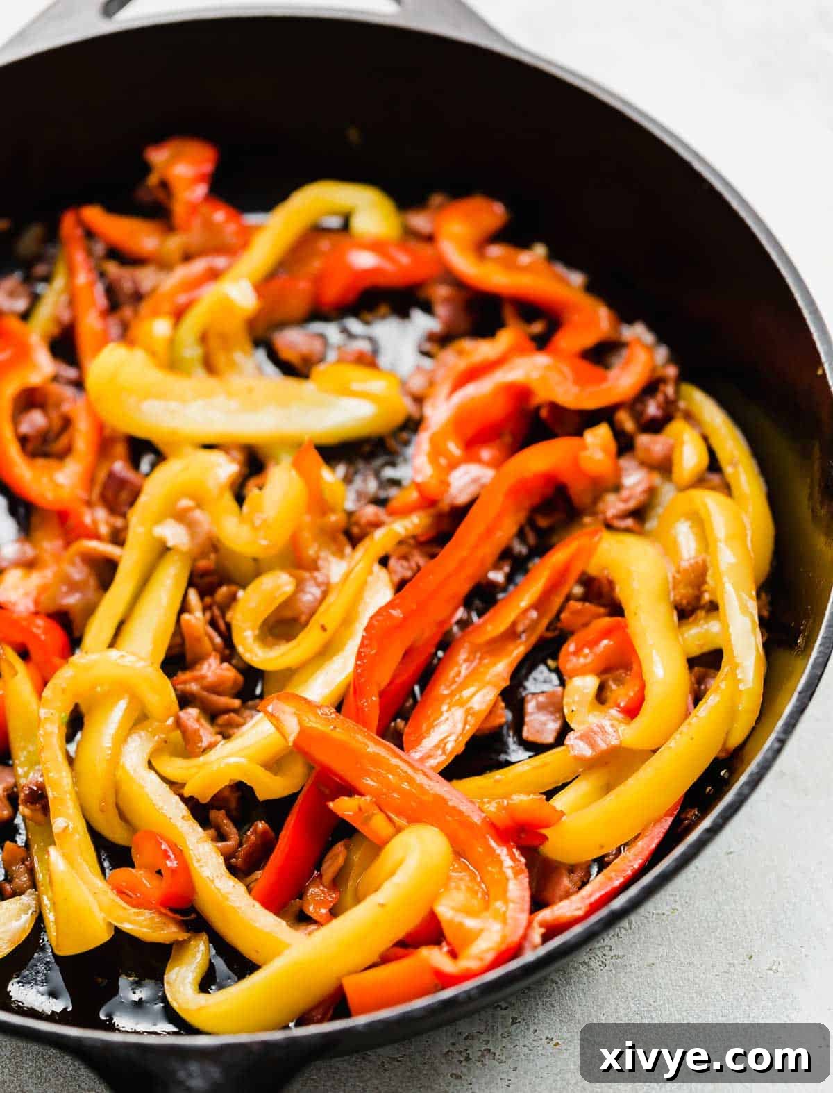 Imperial Chicken 4 Sliced red and yellow peppers with prosciutto in a skillet.