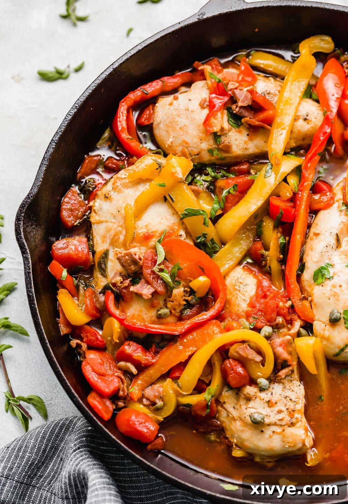 Imperial Chicken 5 Skillet Roman Chicken recipe in a black skillet with sliced red and yellow peppers, fresh herbs, and capers.