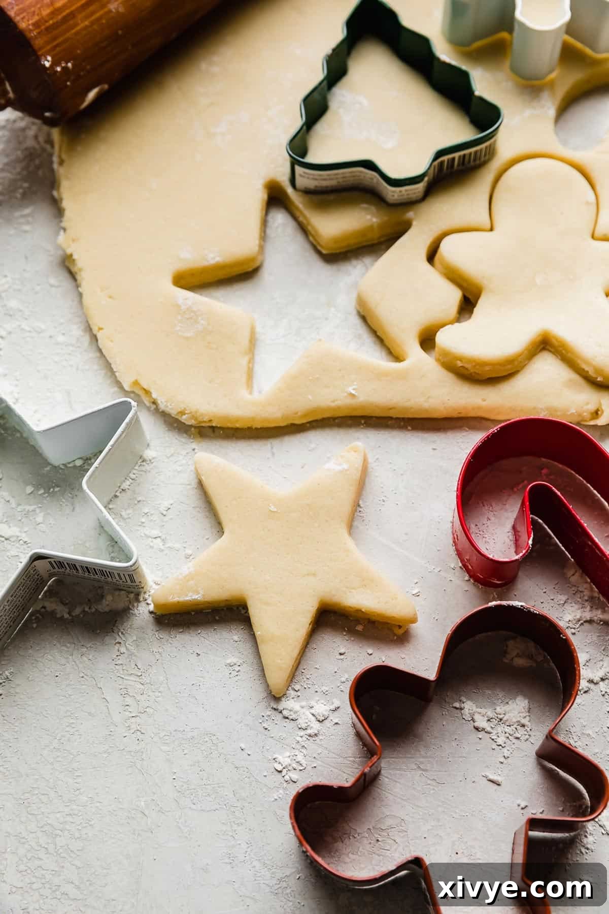 Sugar cookie dough rolled out on a gray surface with a star shape cut out from the dough.