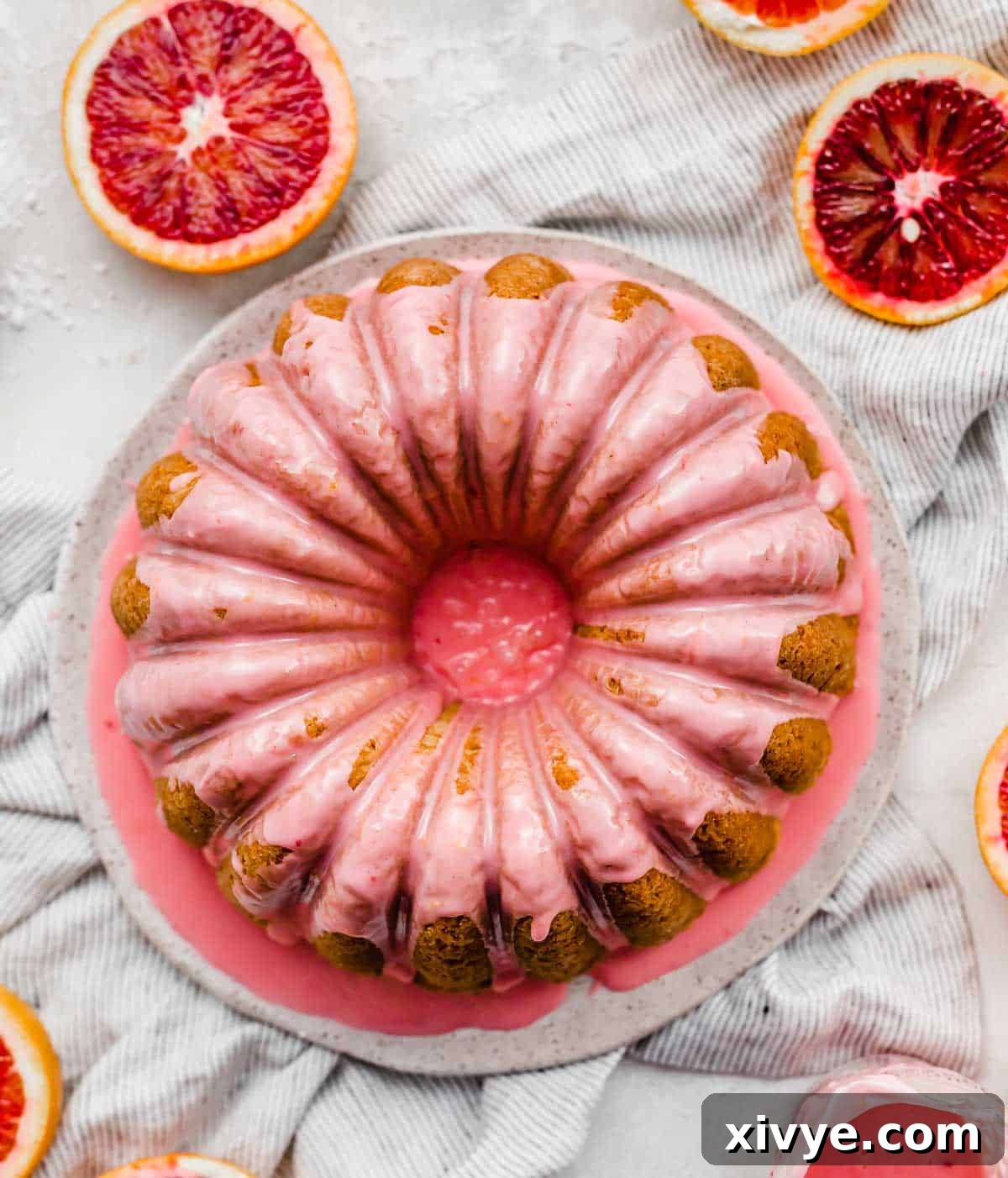 Overhead photo of a pink blood orange glaze on a blood orange bundt cake, decorated with fresh blood orange slices.