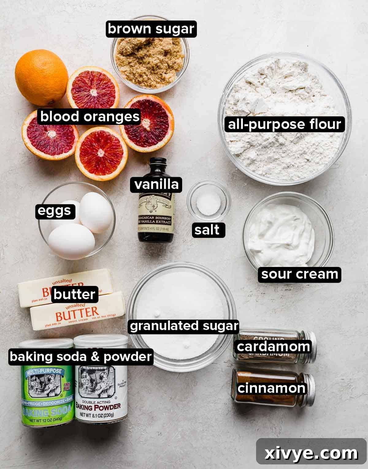 Blood Orange Bundt Cake ingredients portioned into glass bowls on a light gray background, including flour, sugar, butter, and eggs.