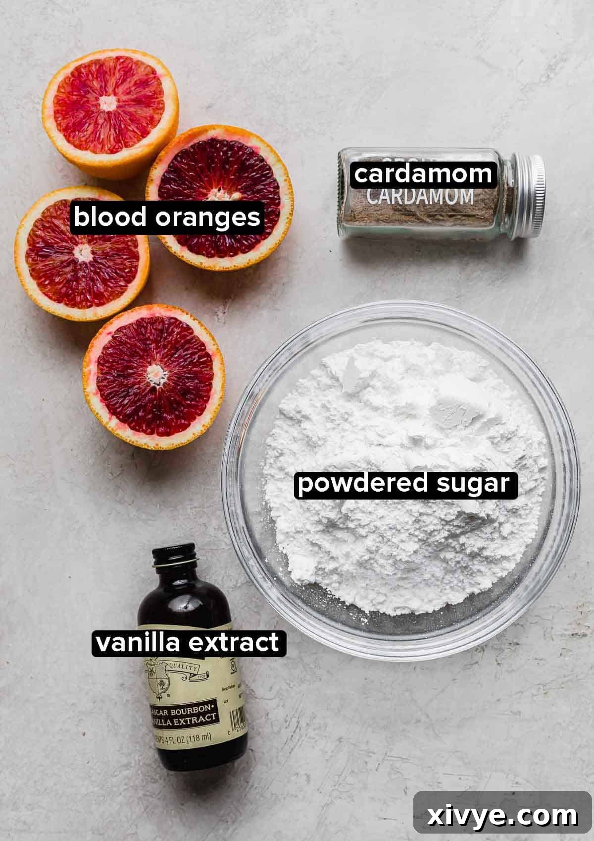 Close-up of blood oranges, powdered sugar, cardamom, and vanilla extract on a light gray background, highlighting the key flavors.