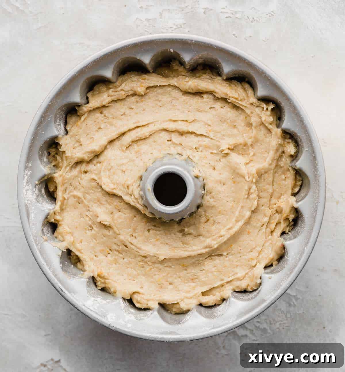 A bundt pan filled with a light yellow colored Blood Orange Bundt Cake batter, ready for baking.