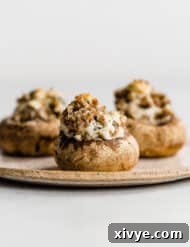 Zesty Italian Sausage Stuffed Mushrooms 9 Three Italian Sausage Stuffed Mushrooms on a tan plate against white background.