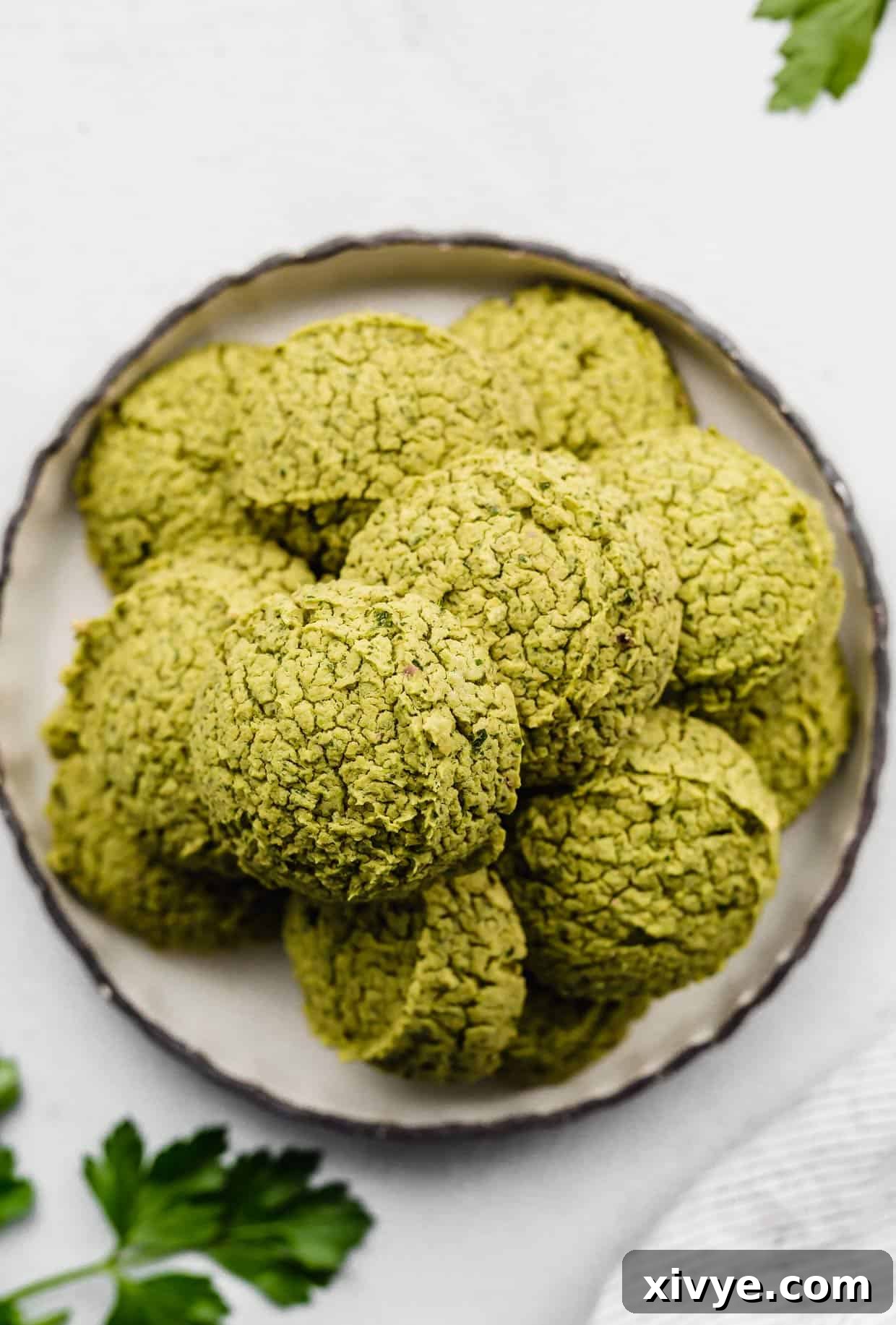 Green Baked Falafel rounds on a black rimmed white plate on a white background.