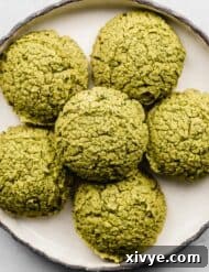 Overhead photo of green falafel on a black rimmed white plate.