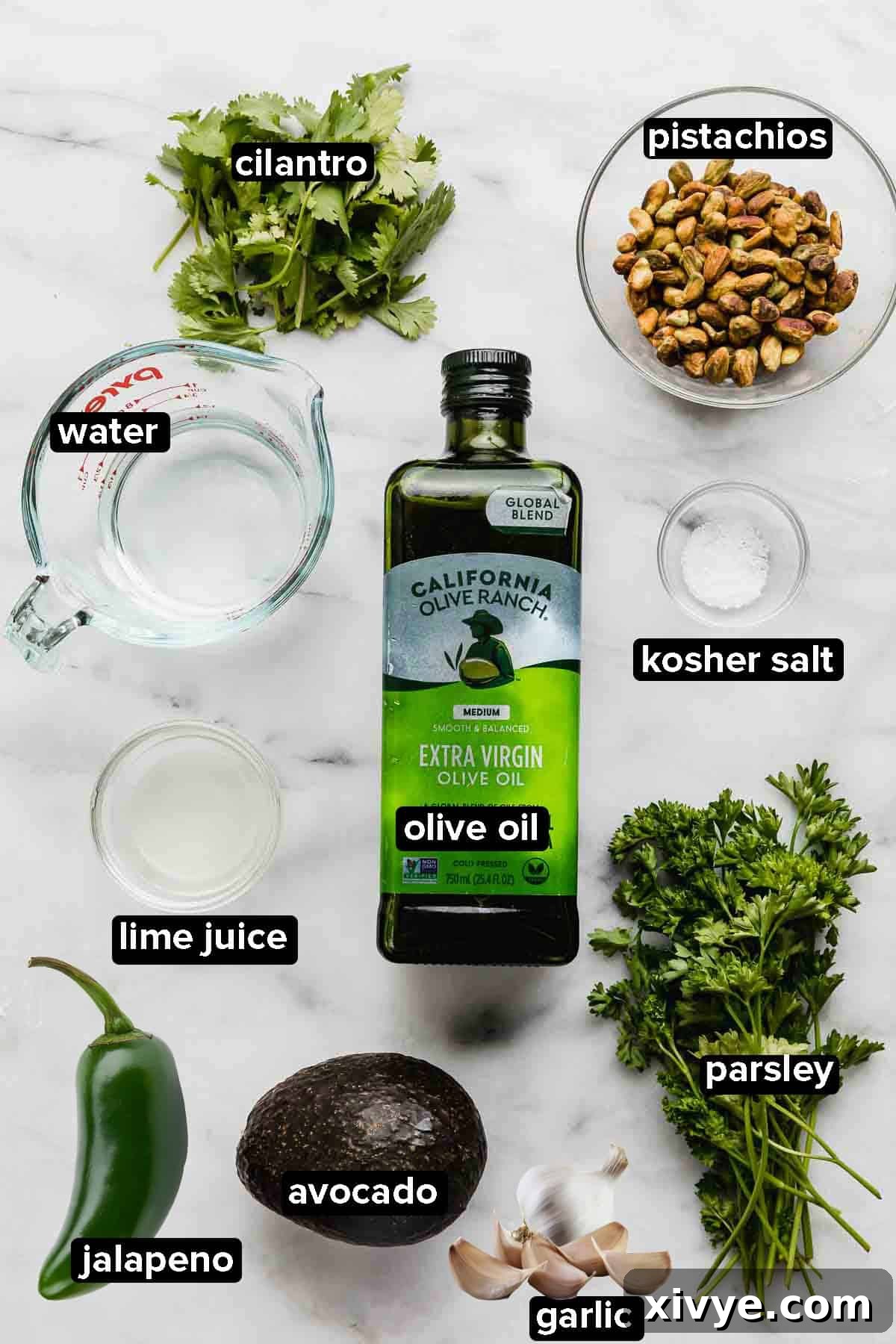 Green Sauce Recipe ingredients on a white background: parsley, cilantro, avocado, jalapeño, garlic, pistachios, and olive oil.