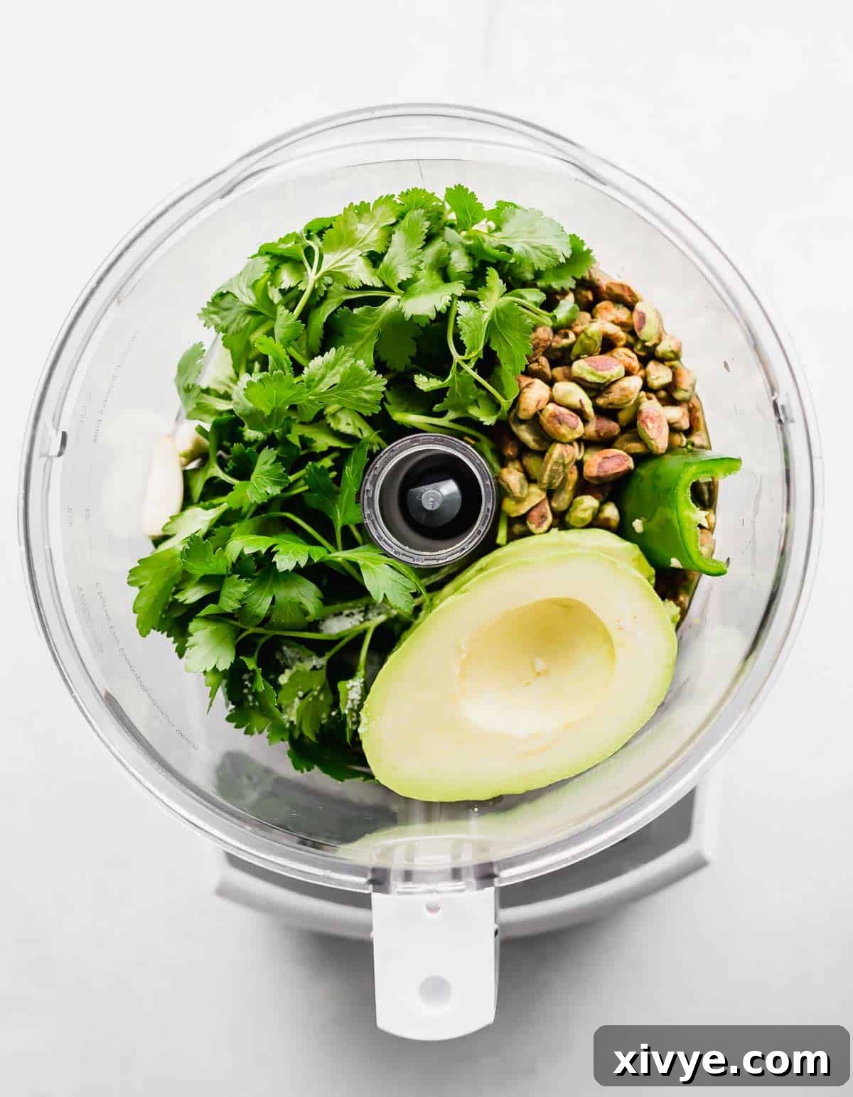 Green Sauce ingredients in a food processor, on a white background.