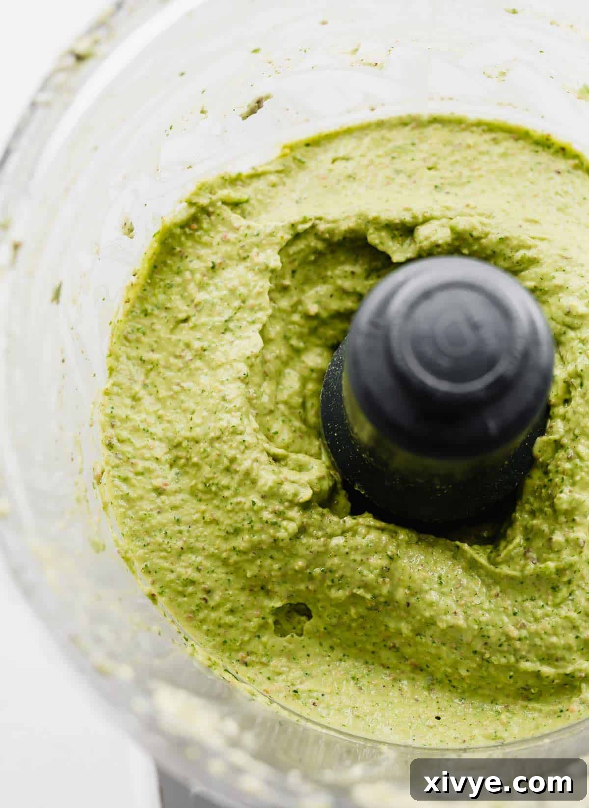 An avocado and herb green sauce in a food processor.