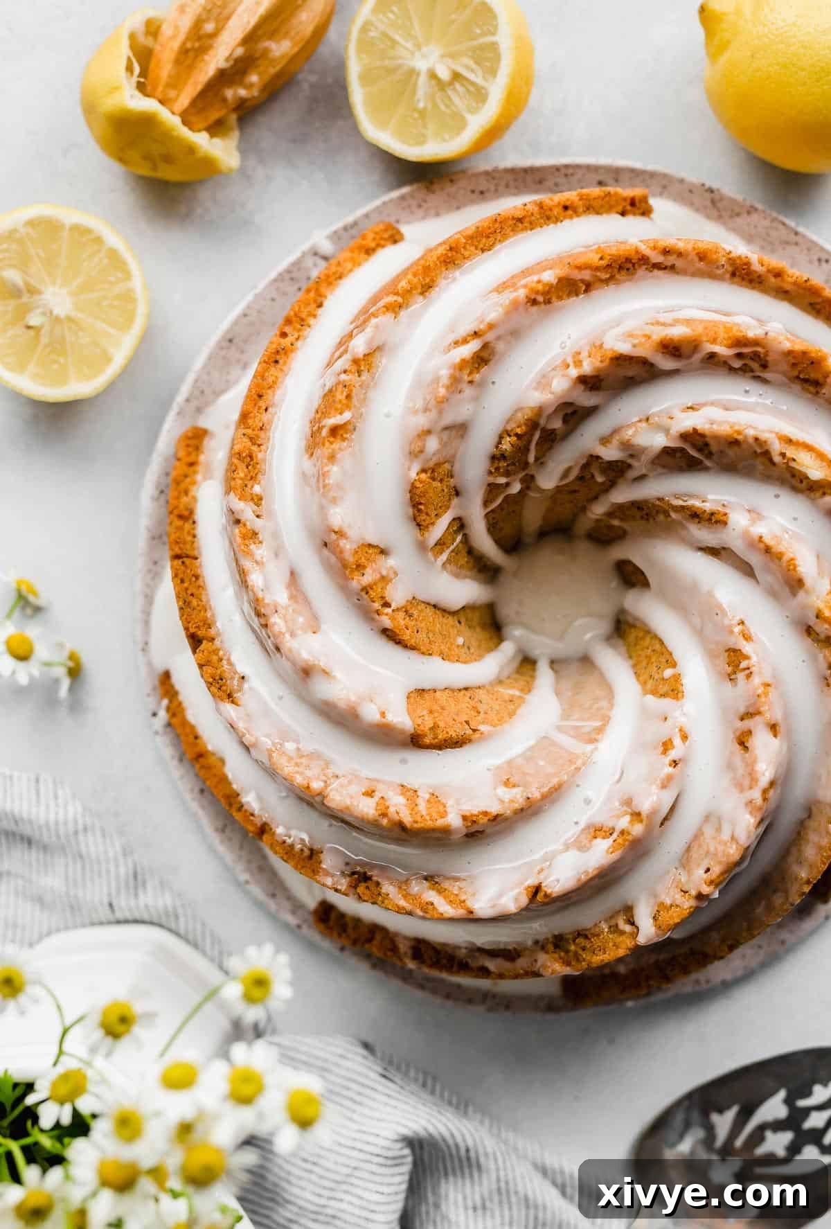An overhead photo of a Lemon Poppy Seed Bundt Cake topped with a white glaze with sliced lemons around the cake, showcasing its beautiful form and vibrant citrus appeal.