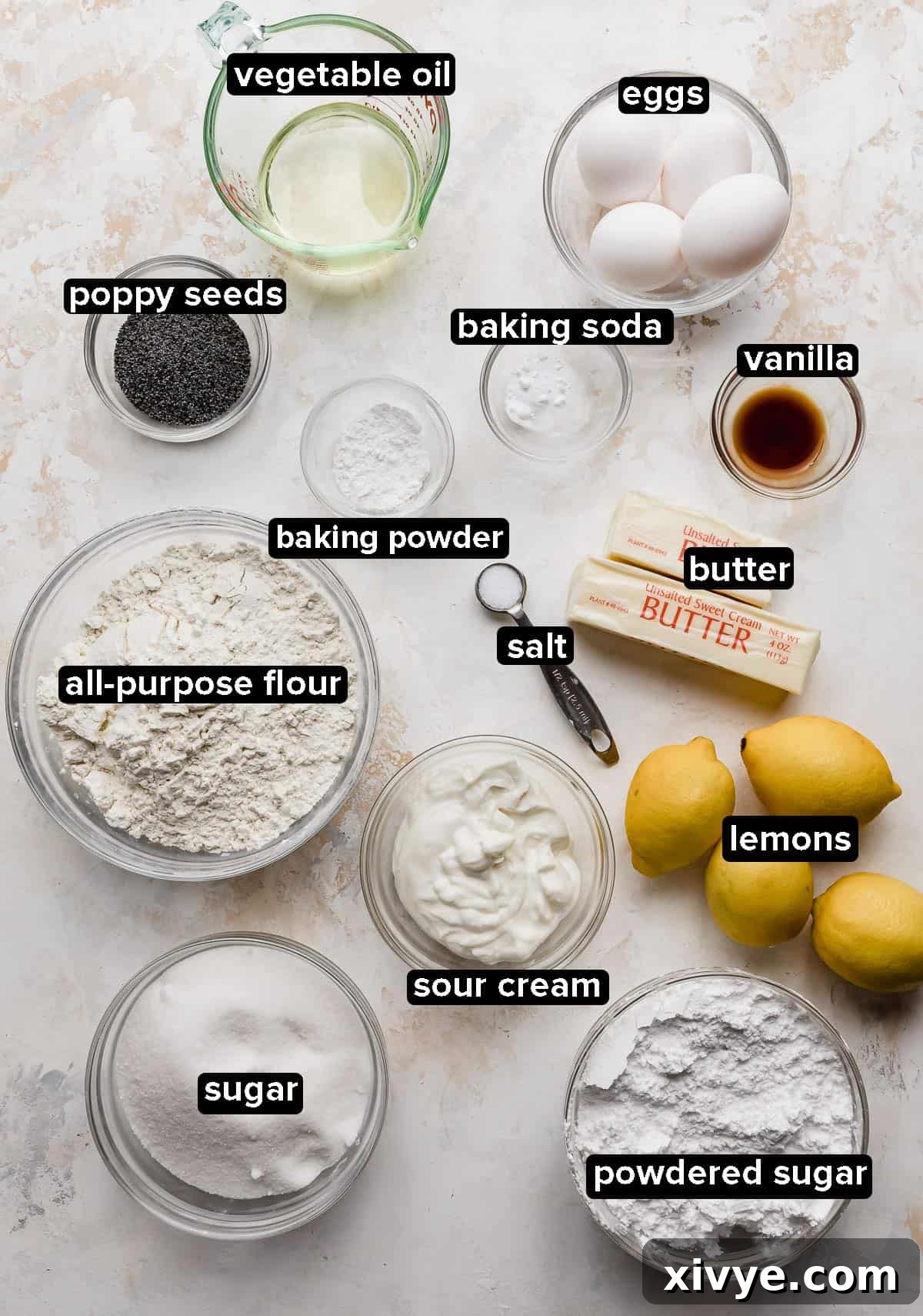 Lemon Poppy Seed Bundt Cake ingredients portioned into glass bowls on a cream textured background, ready for baking.