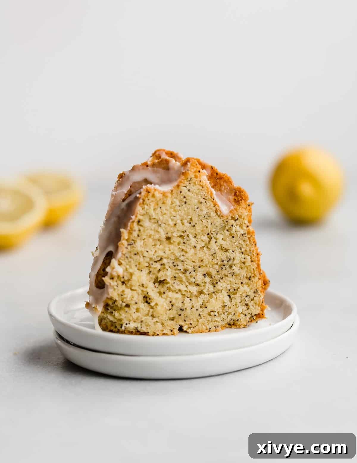 A perfect slice of Lemon Poppy Seed Bundt Cake on a white plate, showing the moist crumb and poppy seeds.