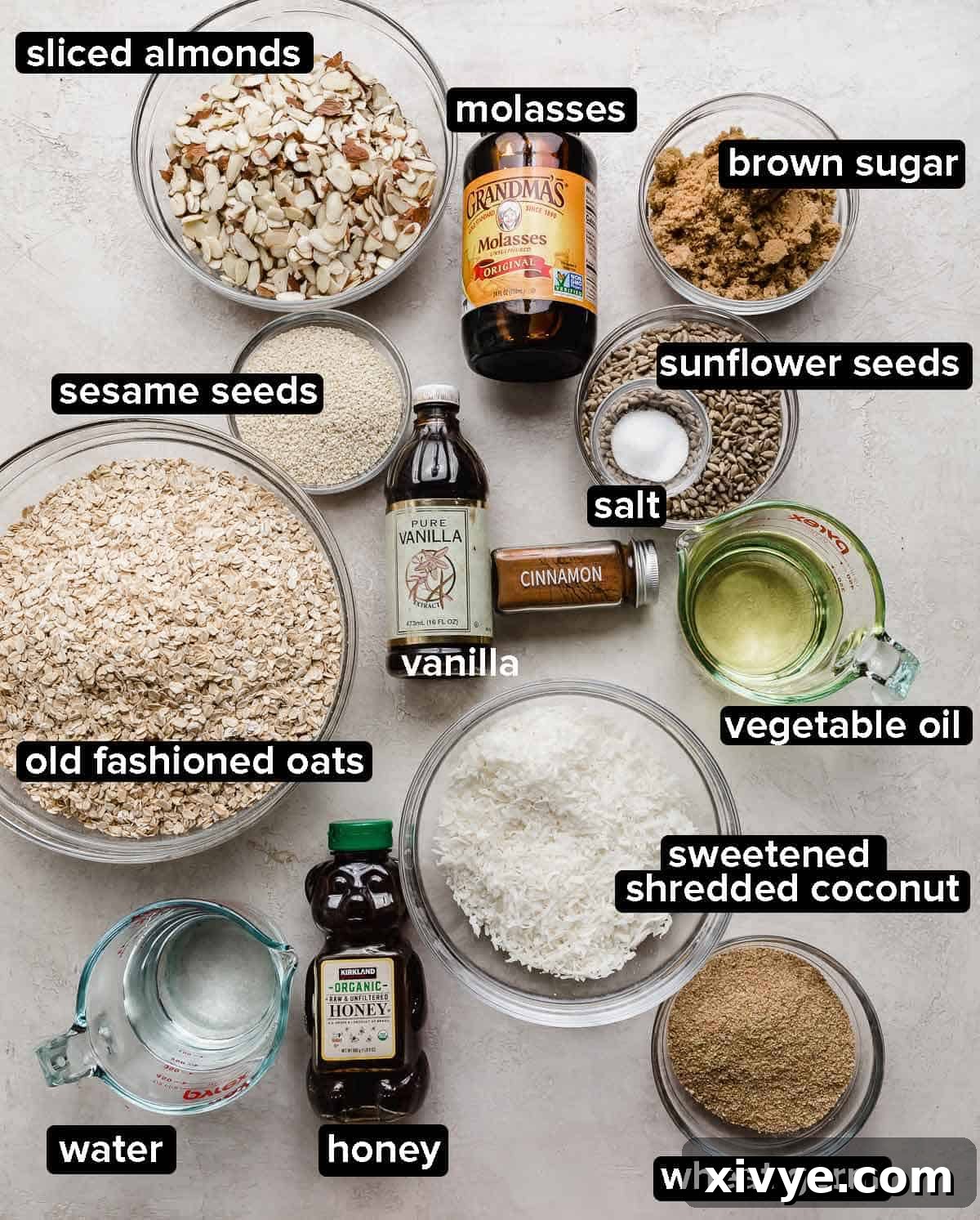 An easy Granola Recipe ingredients portioned into glass bowls on a white background, ingredients include cinnamon, nuts, oats, honey, molasses, wheat germ, vegetable oil, and brown sugar.