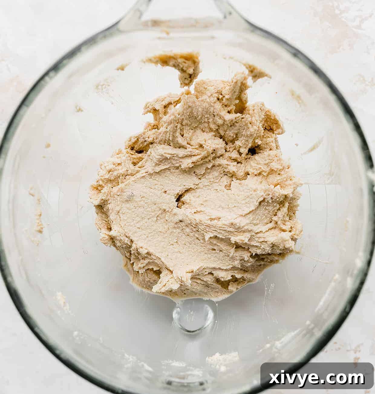 Smooth, light, and fluffy creamed butter and sugar mixture in a clear glass mixing bowl, indicating perfect aeration.