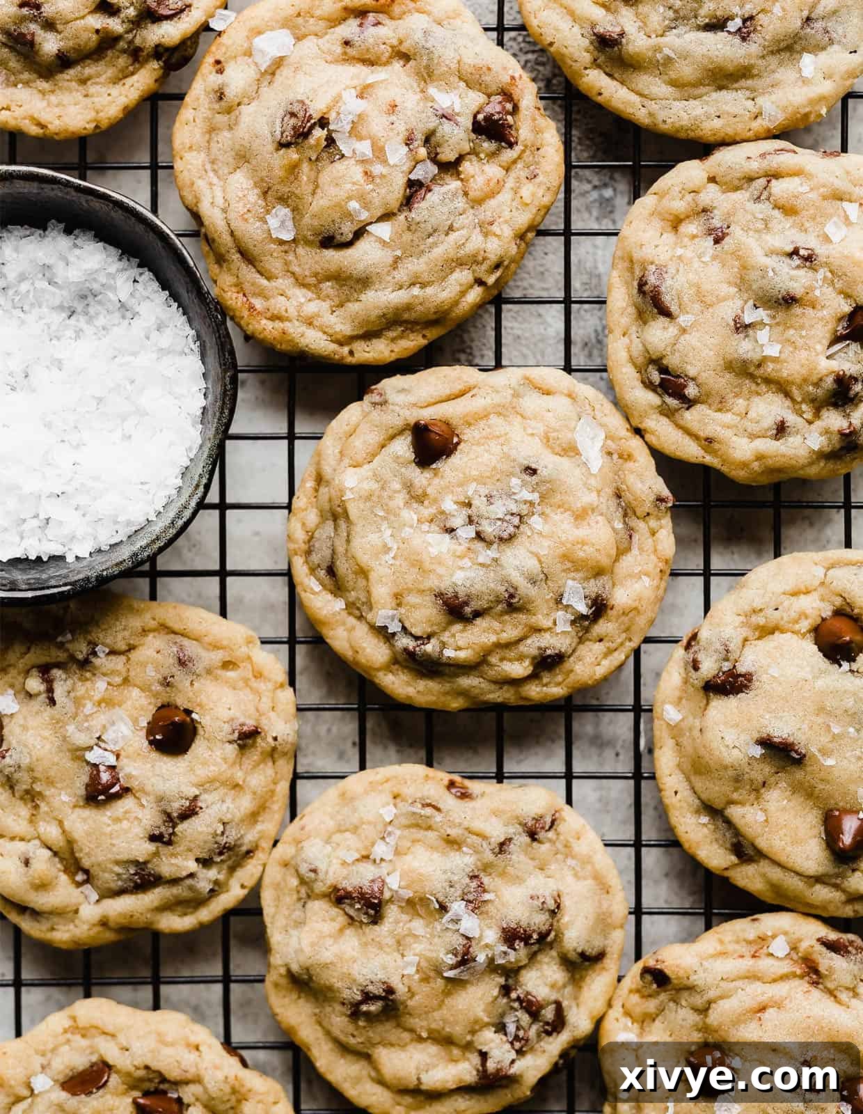 A stack of golden brown chocolate chip cookies, still warm and inviting, cooling on a black wire rack.