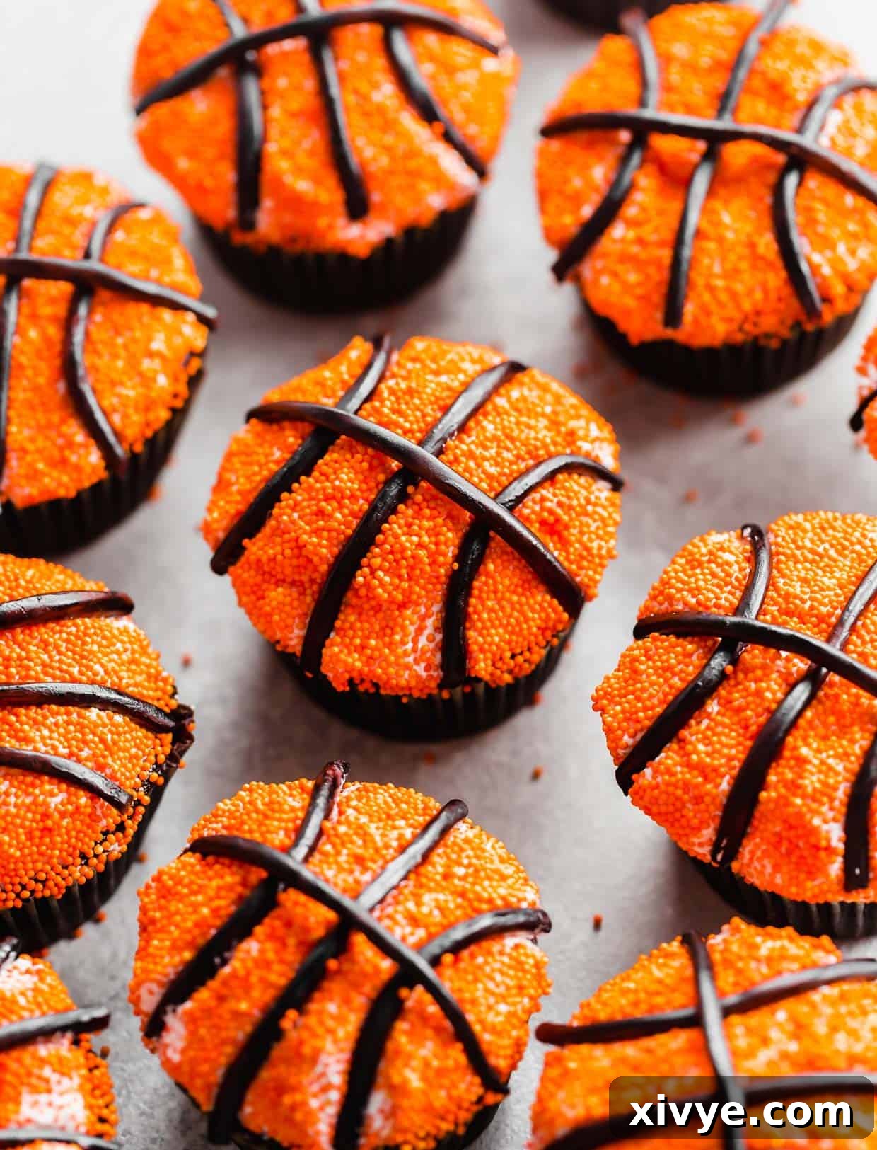 Slam Dunk Sweets 2 Basketball Cupcakes decorated with small orange nonpareil sprinkles and black licorice laces, resembling miniature basketballs.