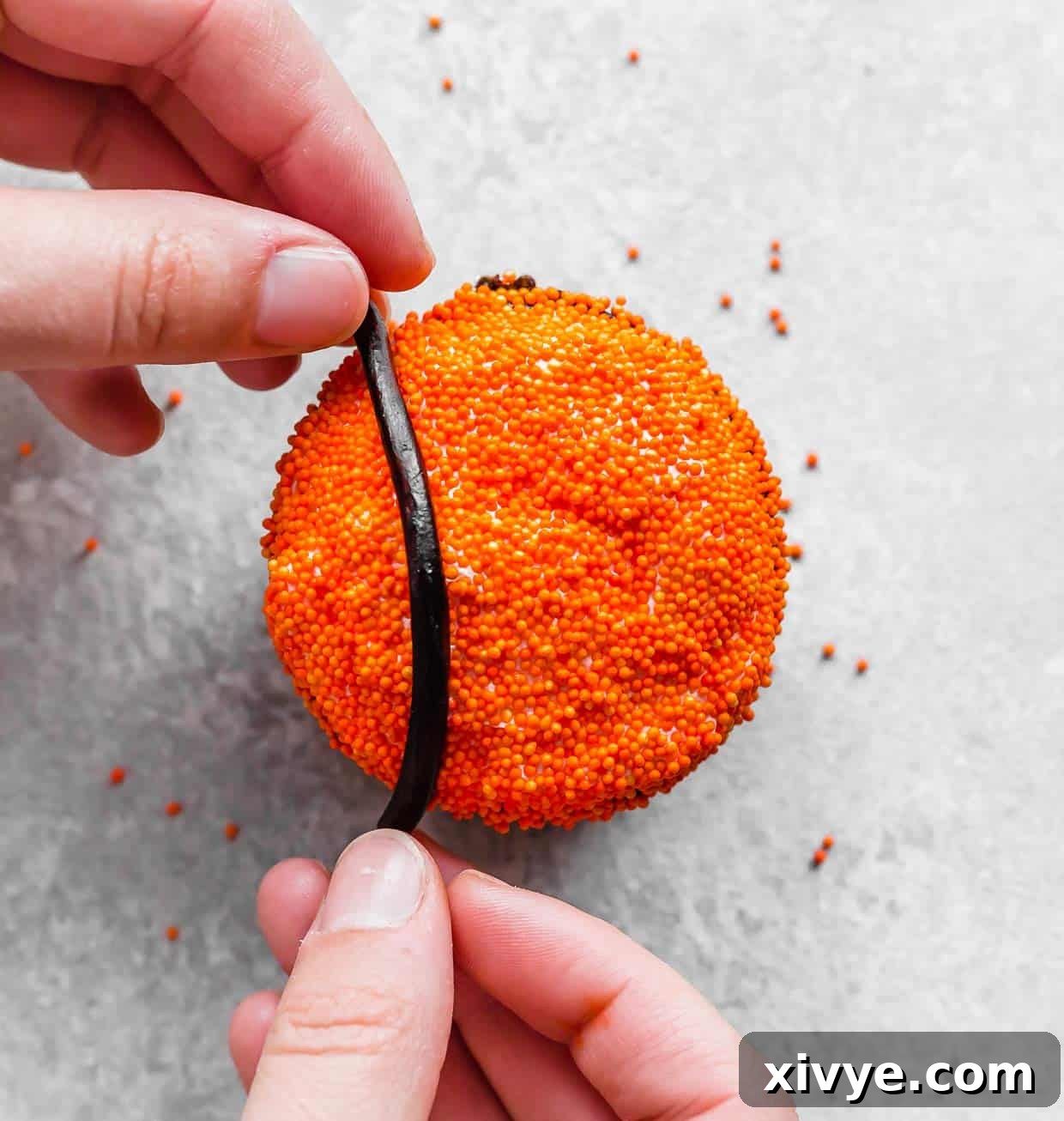Slam Dunk Sweets 5 A hand carefully placing a black licorice lace onto an orange sprinkled cupcake to form the basketball design.