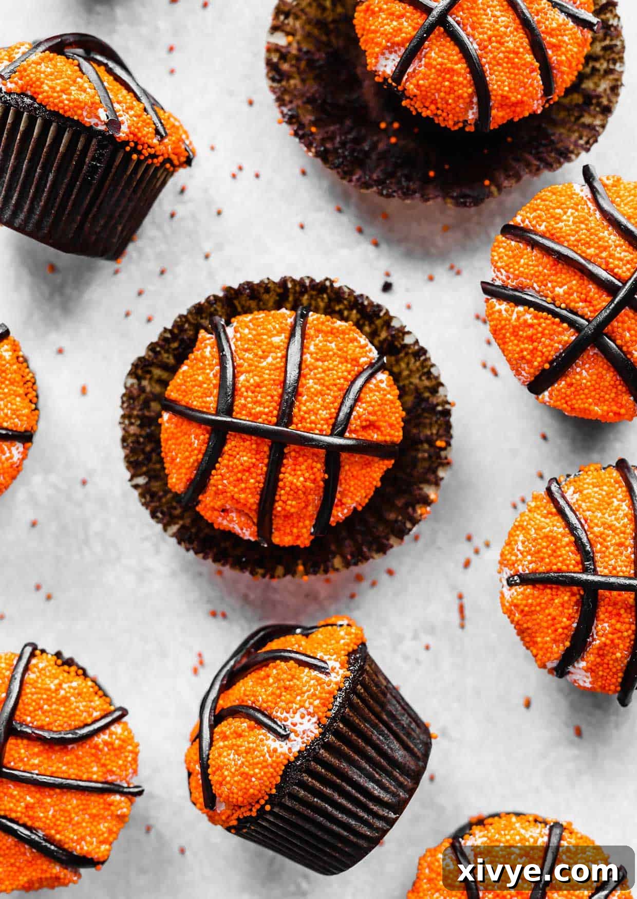 Slam Dunk Sweets 6 A collection of decorated Basketball Cupcakes arranged on a grey background, showcasing their festive and sporty design.