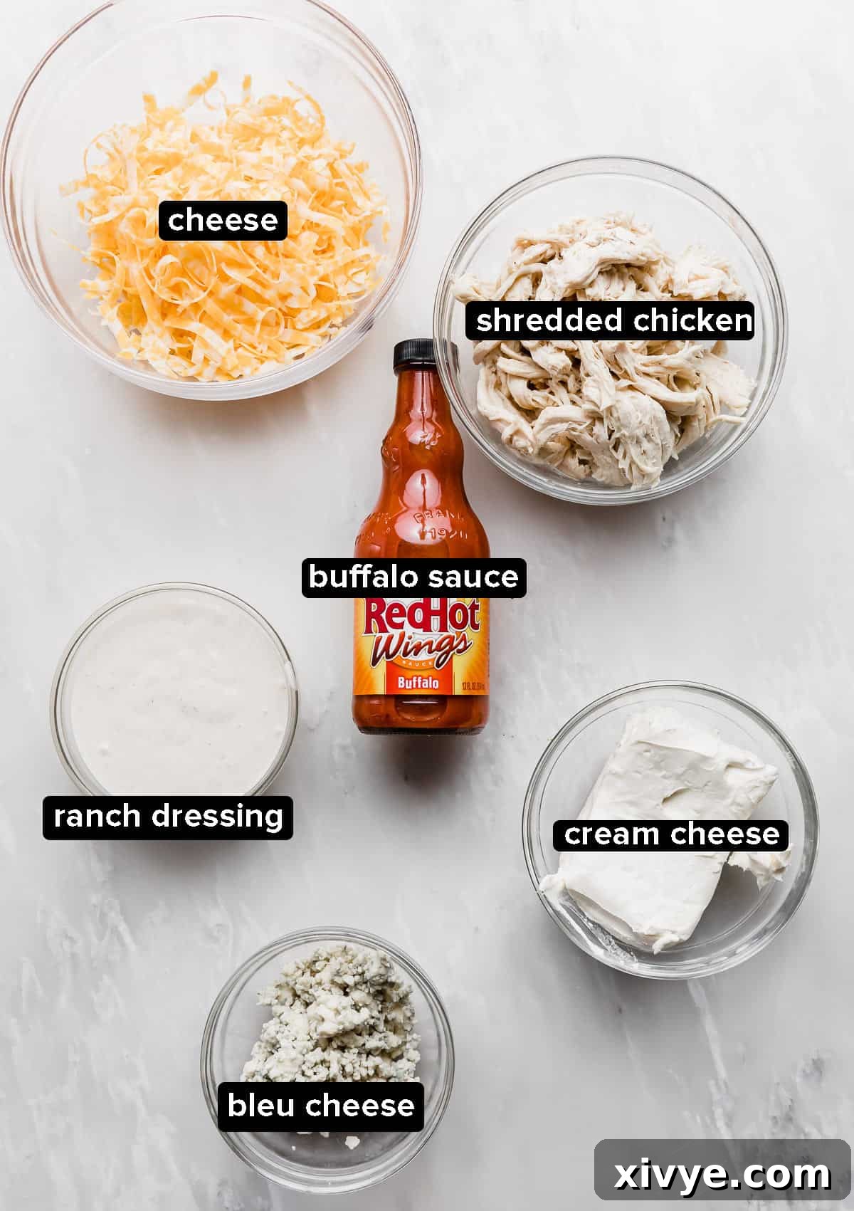 The Ultimate Buffalo Chicken Dip 3 All the fresh ingredients for Buffalo Chicken Dip with blue cheese arranged on a stylish marble table.