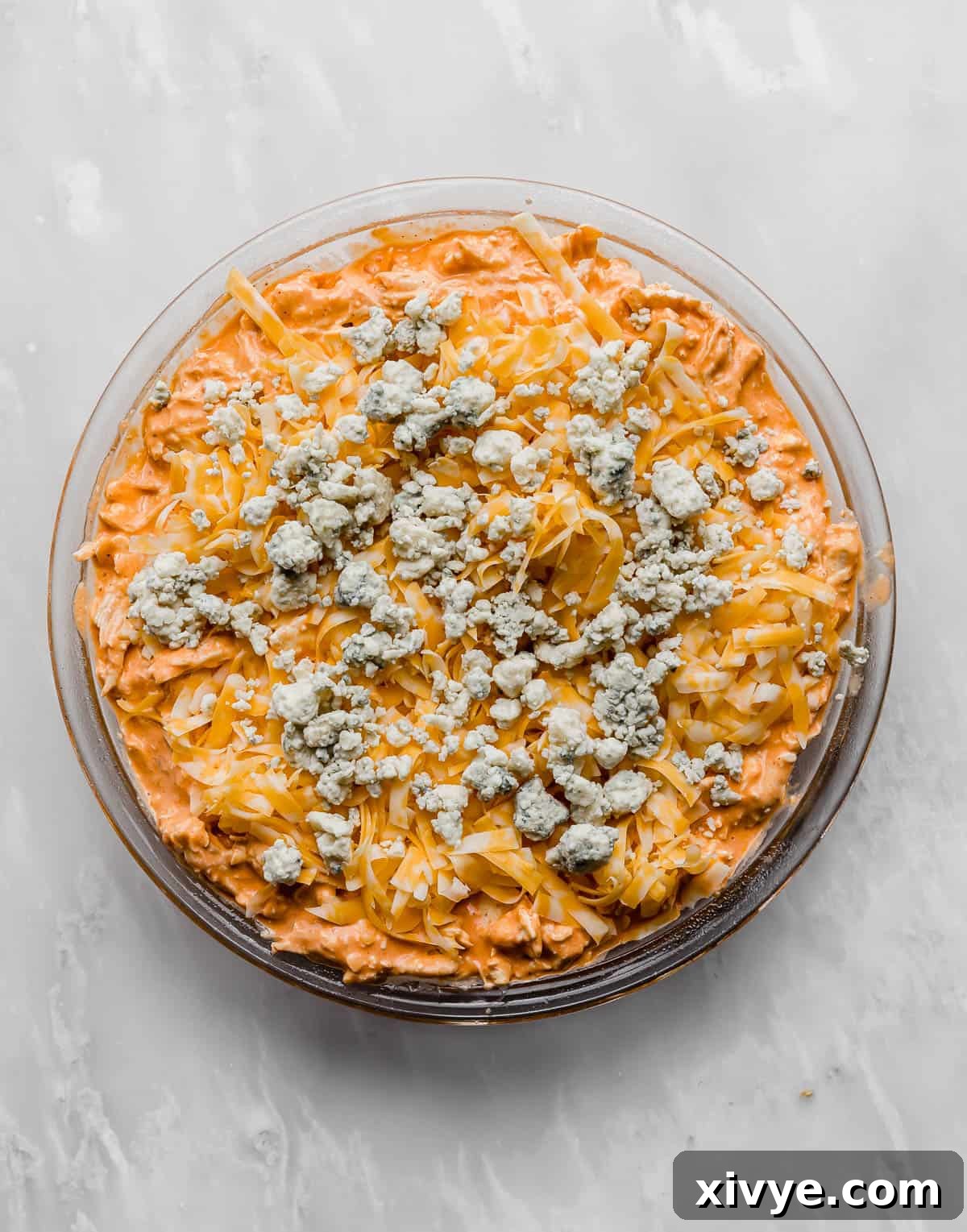 The Ultimate Buffalo Chicken Dip 7 The perfectly baked Buffalo Chicken Dip, golden and bubbly, topped with crumbled blue cheese in a round baking dish, ready for serving.