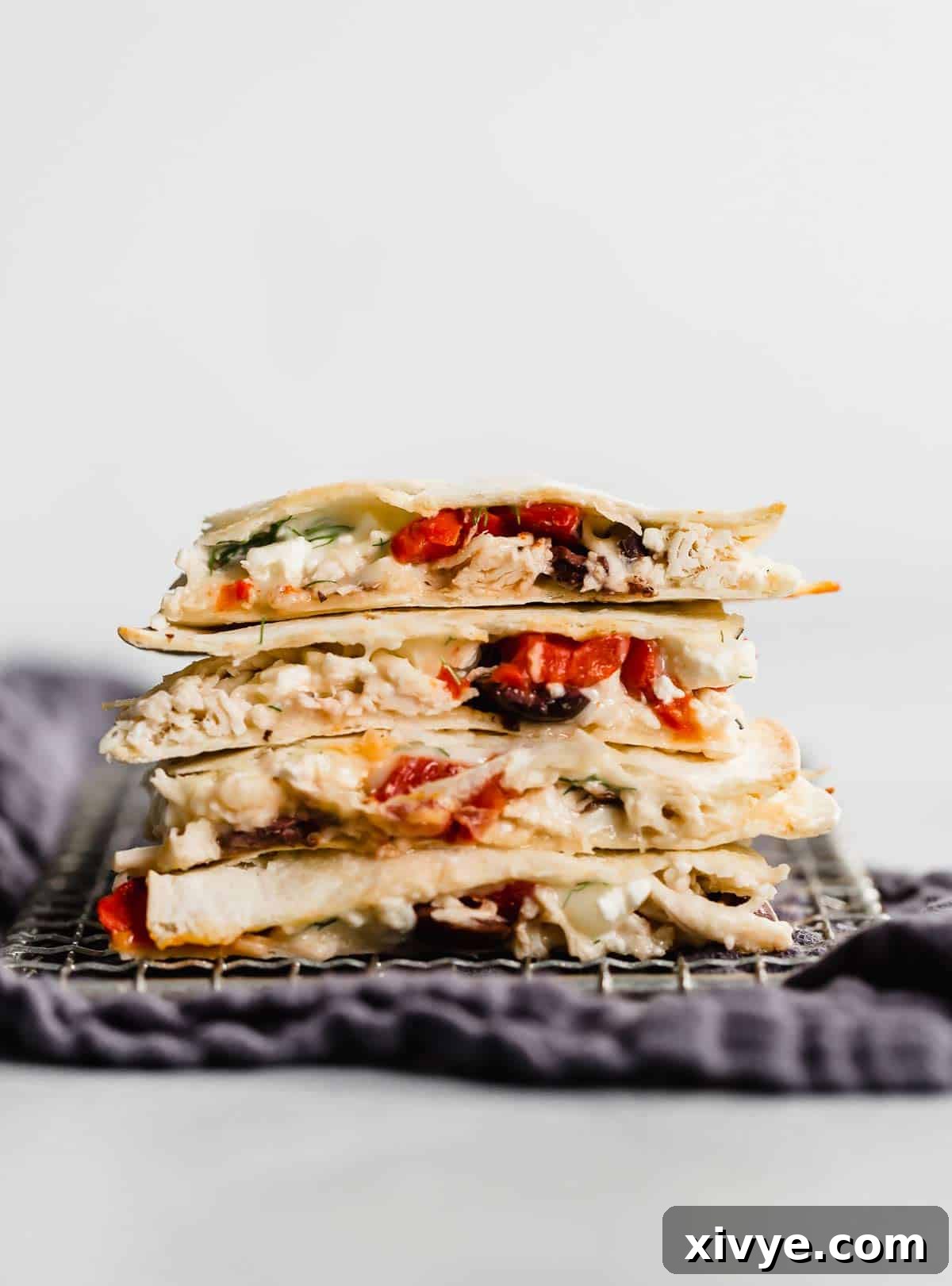 A Greek Quesadilla cut into quarters and stacked on top of each other against a white background.