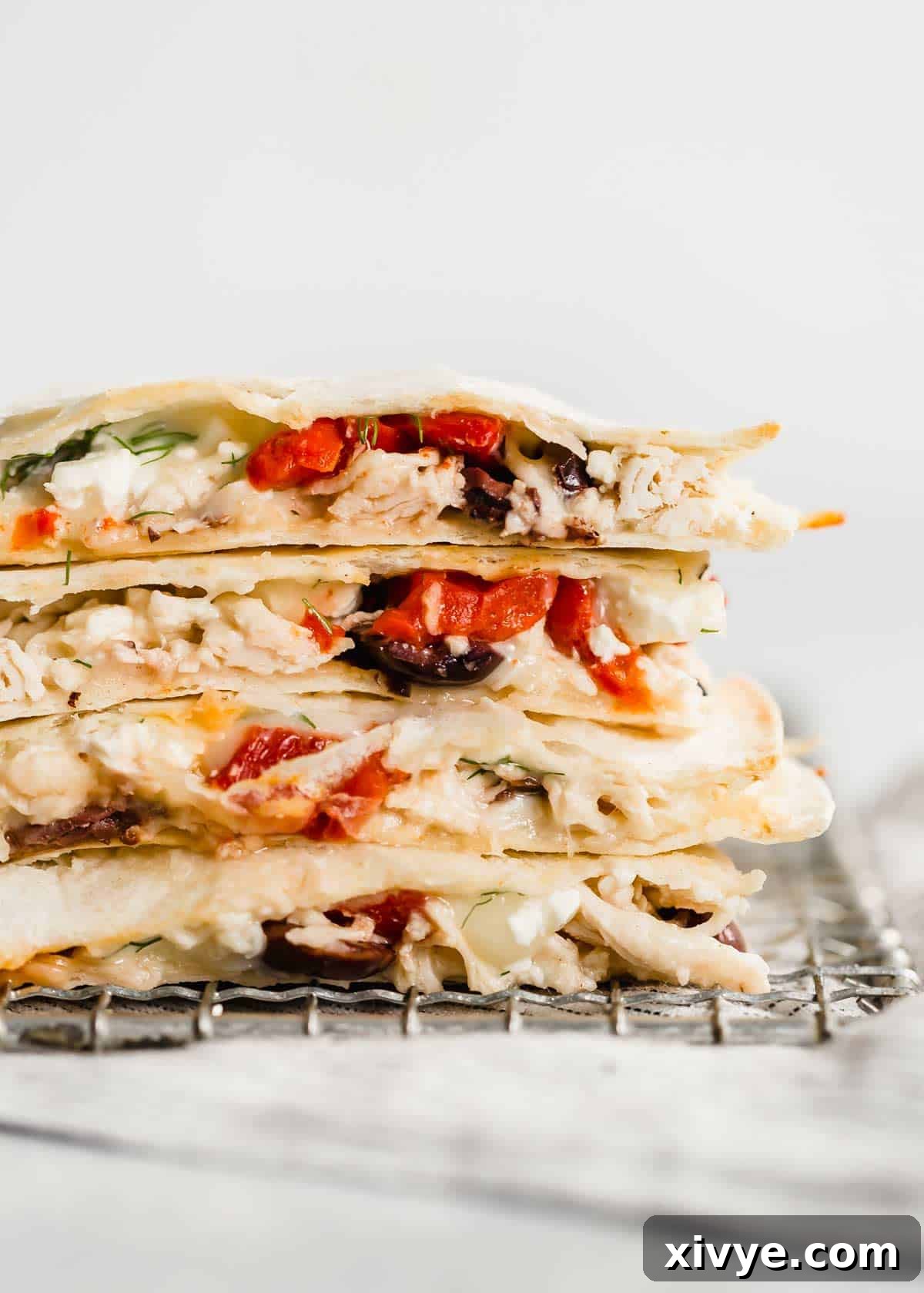 Close up photo of the a cut Greek Quesadilla with Kalamata olives, roasted red peppers, and shredded chicken.