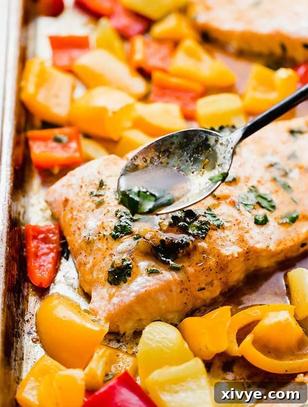 Fiery Citrus Salmon Sheet Pan Dinner 2 Sheet Pan Chili Lime Salmon on a baking sheet with chili lime sauce drizzled overtop. Cooked salmon surrounded by colorful bell peppers.