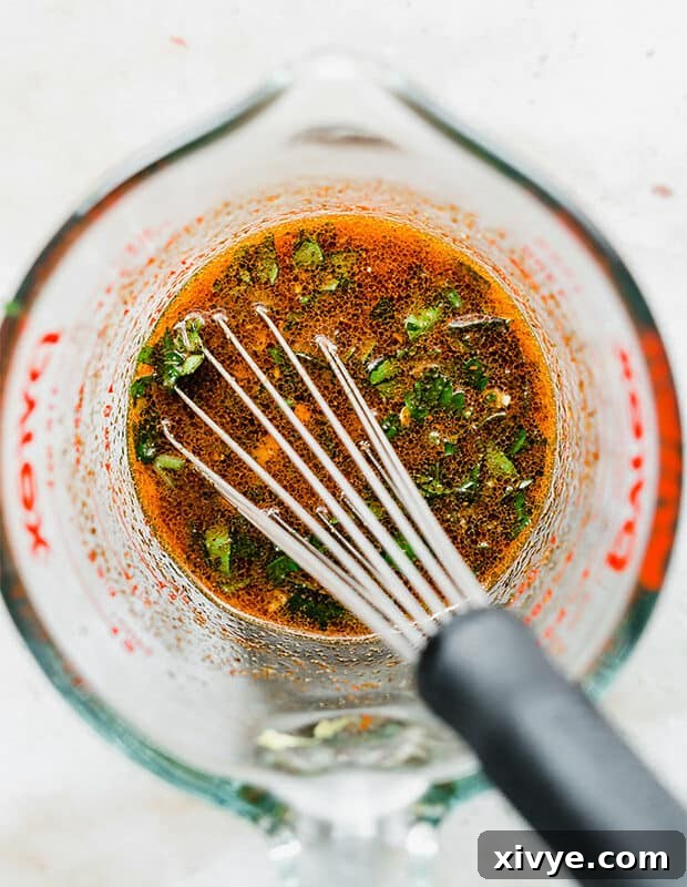 Fiery Citrus Salmon Sheet Pan Dinner 3 A glass measuring cup with freshly mixed chili lime sauce.