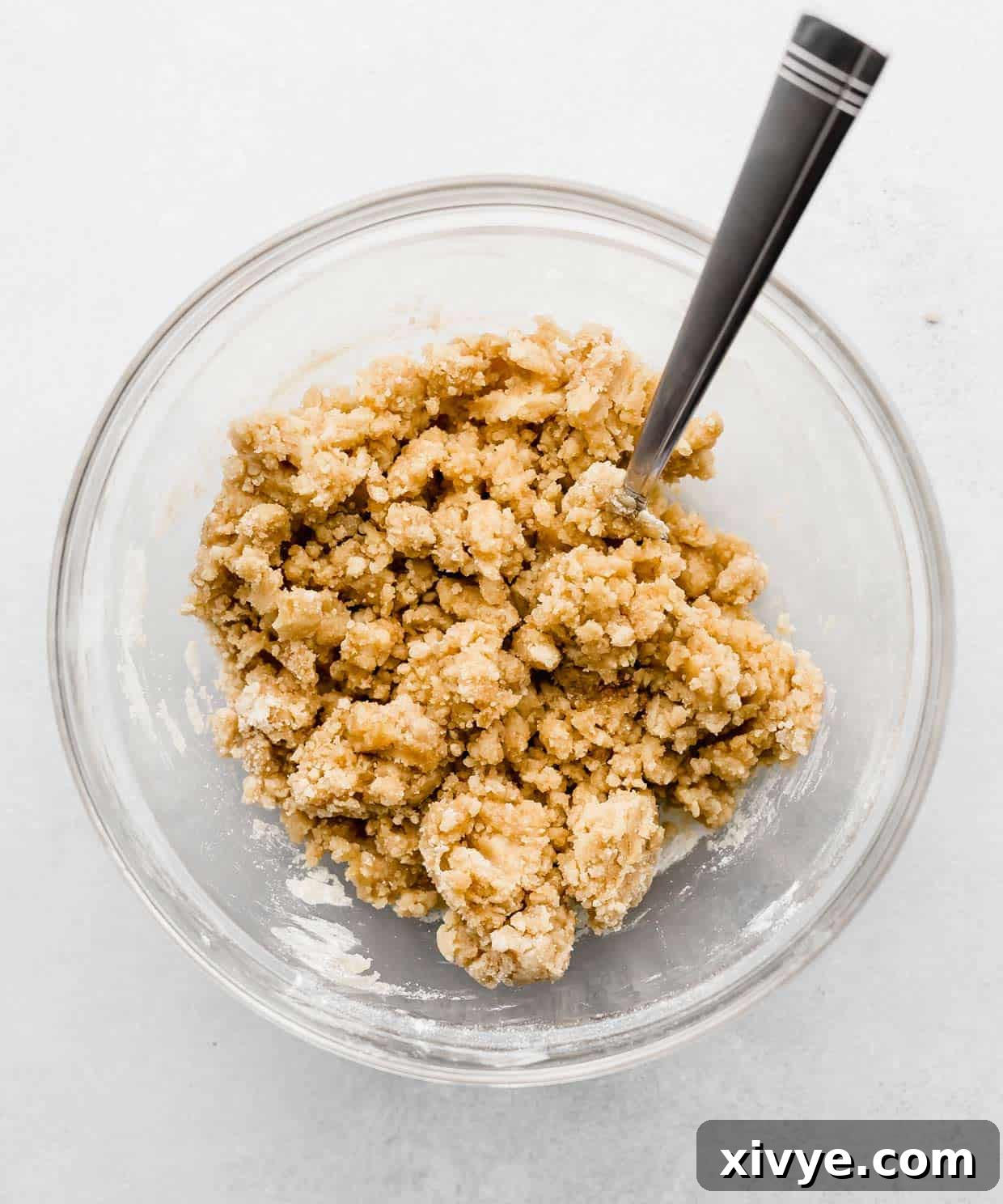 Zesty and Tender Lemon Poppy Seed Muffins 4 A crumbly crumb topping in a glass bowl on a white background.