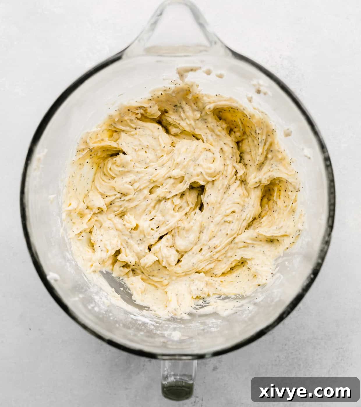 Zesty and Tender Lemon Poppy Seed Muffins 5 Lemon Poppy Seed Muffin batter in a glass mixing bowl on a white background.