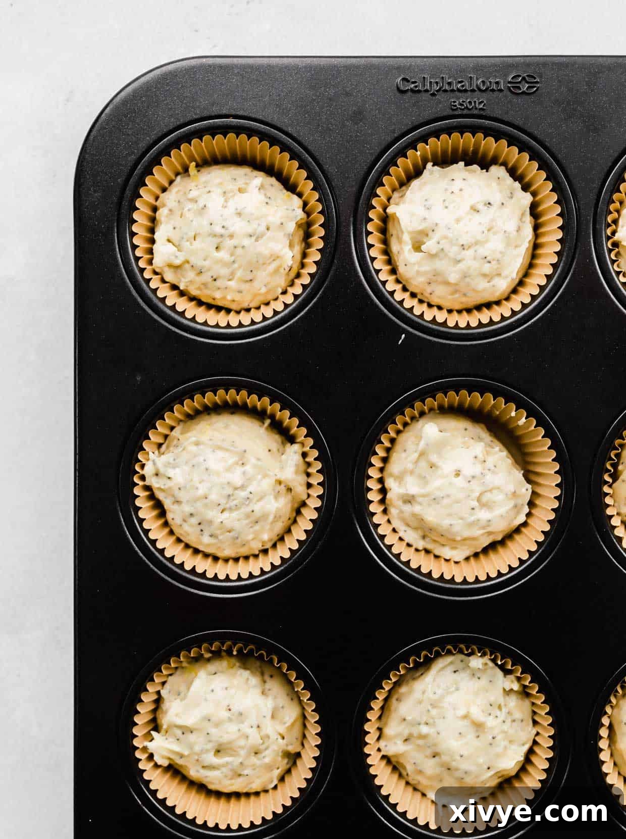 Zesty and Tender Lemon Poppy Seed Muffins 6 Lemon Poppy Seed Muffin batter in Kraft paper lined muffin tins.