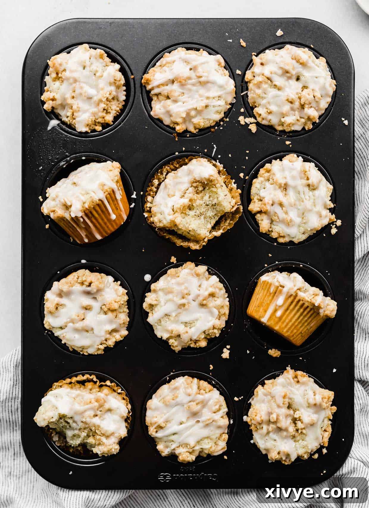 Zesty and Tender Lemon Poppy Seed Muffins 8 A muffin tin with baked Lemon Poppy Seed Muffins with a crumb topping and glaze.