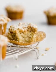 Zesty and Tender Lemon Poppy Seed Muffins 10 A bite taken out of a Lemon Poppy Seed Muffin that's on a circular wire cooling rack.