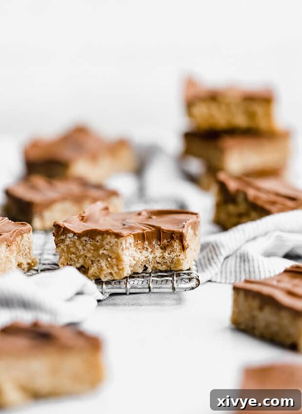 A single Scotcharoo bar on a wire rack with a bite taken out, showing the chewy peanut butter base and smooth topping.