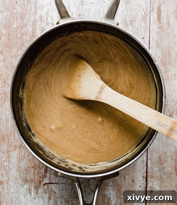 A saucepan on the stove with a mixture of corn syrup and sugar, ready for peanut butter to be stirred in.