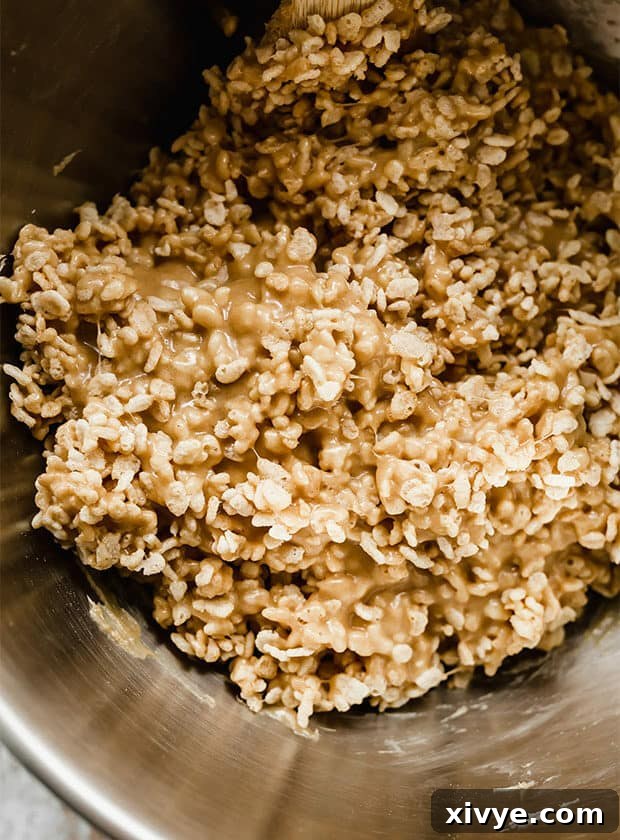 Rice Krispies cereal being coated with the hot peanut butter and corn syrup mixture for Scotcharoos.