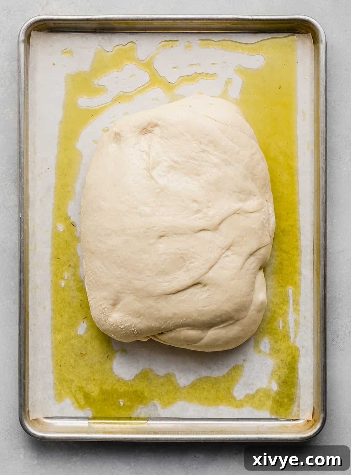 Focaccia Bread dough shaped in a rectangle on an oil-covered baking sheet, ready for the dimpling process.