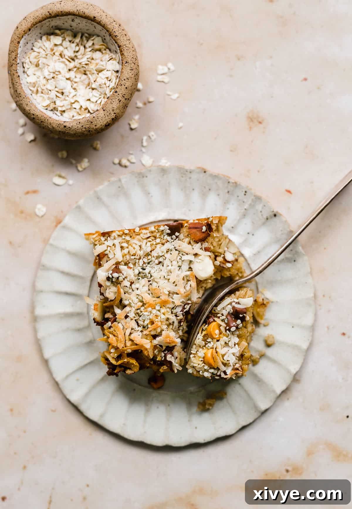 A square of Baked Oatmeal Cake on a plate with a fork cutting into the corner of the slice, showing its inviting texture.