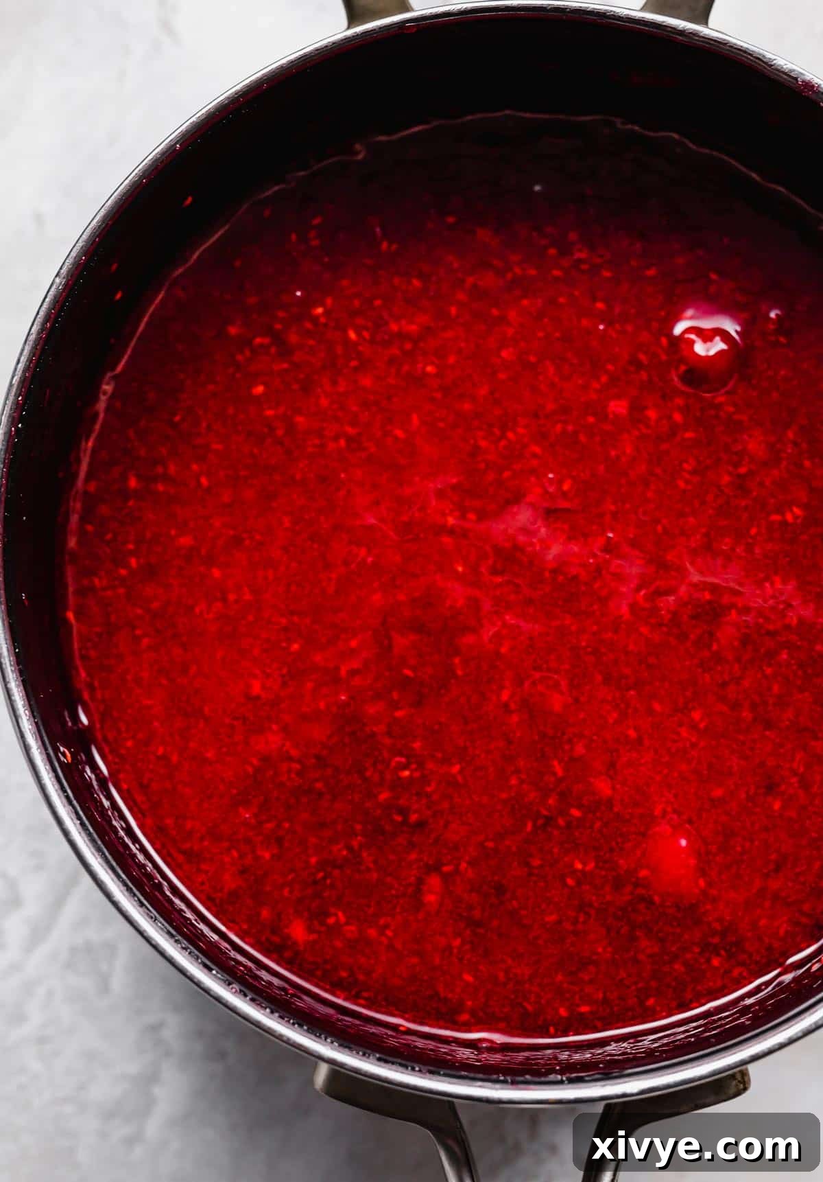 No-Fuss Raspberry Freezer Jam 7 A black saucepan with a red raspberry sauce in it.