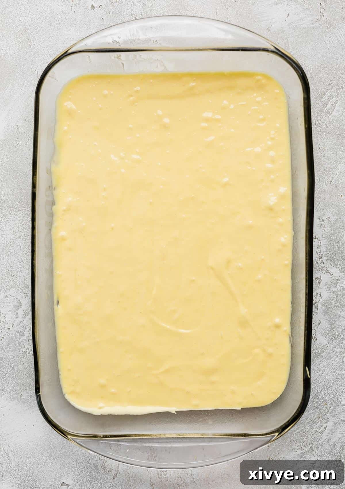 Smooth lemon cake batter evenly spread in a rectangular glass baking dish, ready for the oven.