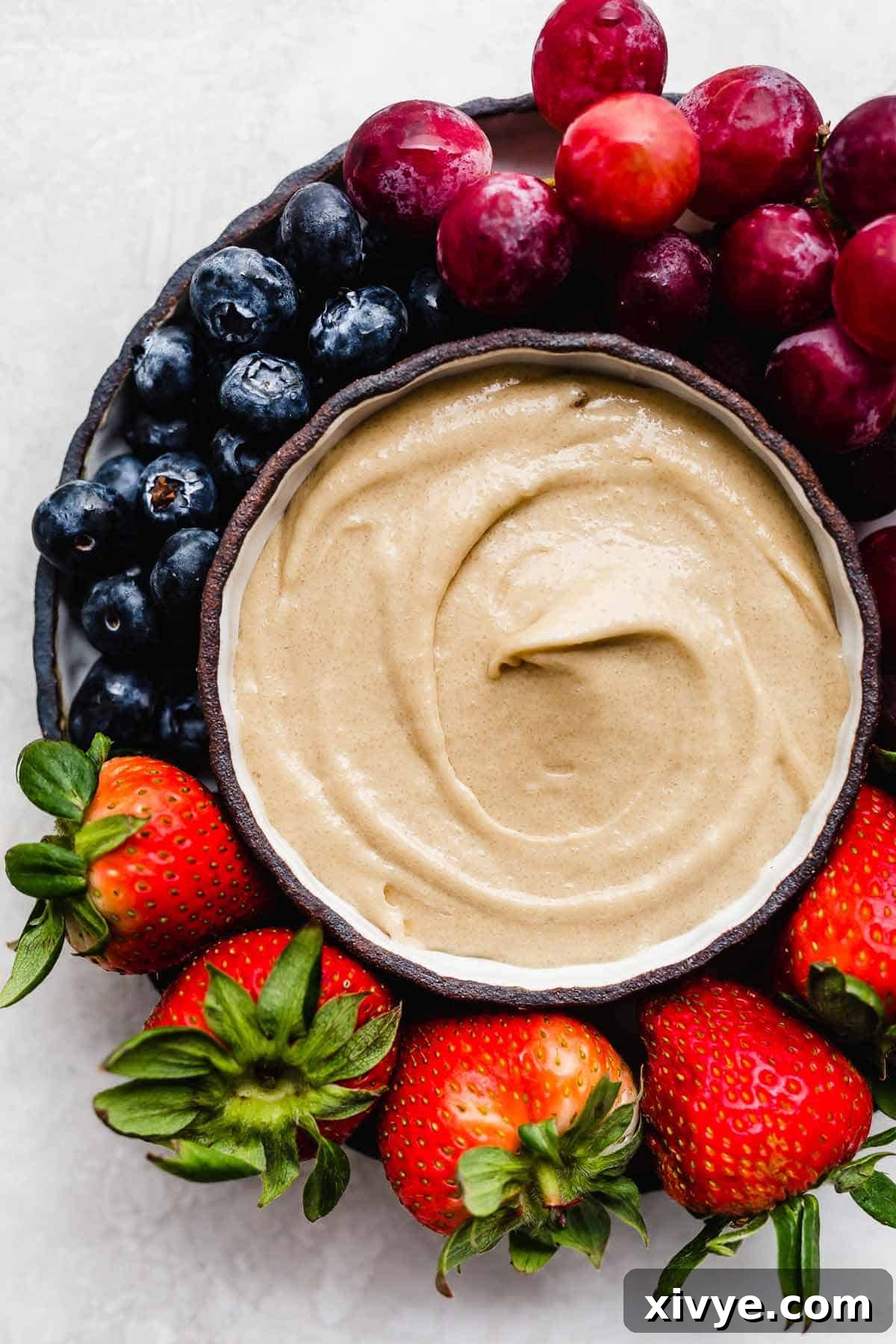 Cream Cheese Fruit Dip in a black bowl with strawberries, grapes, and blueberries around the bowl.