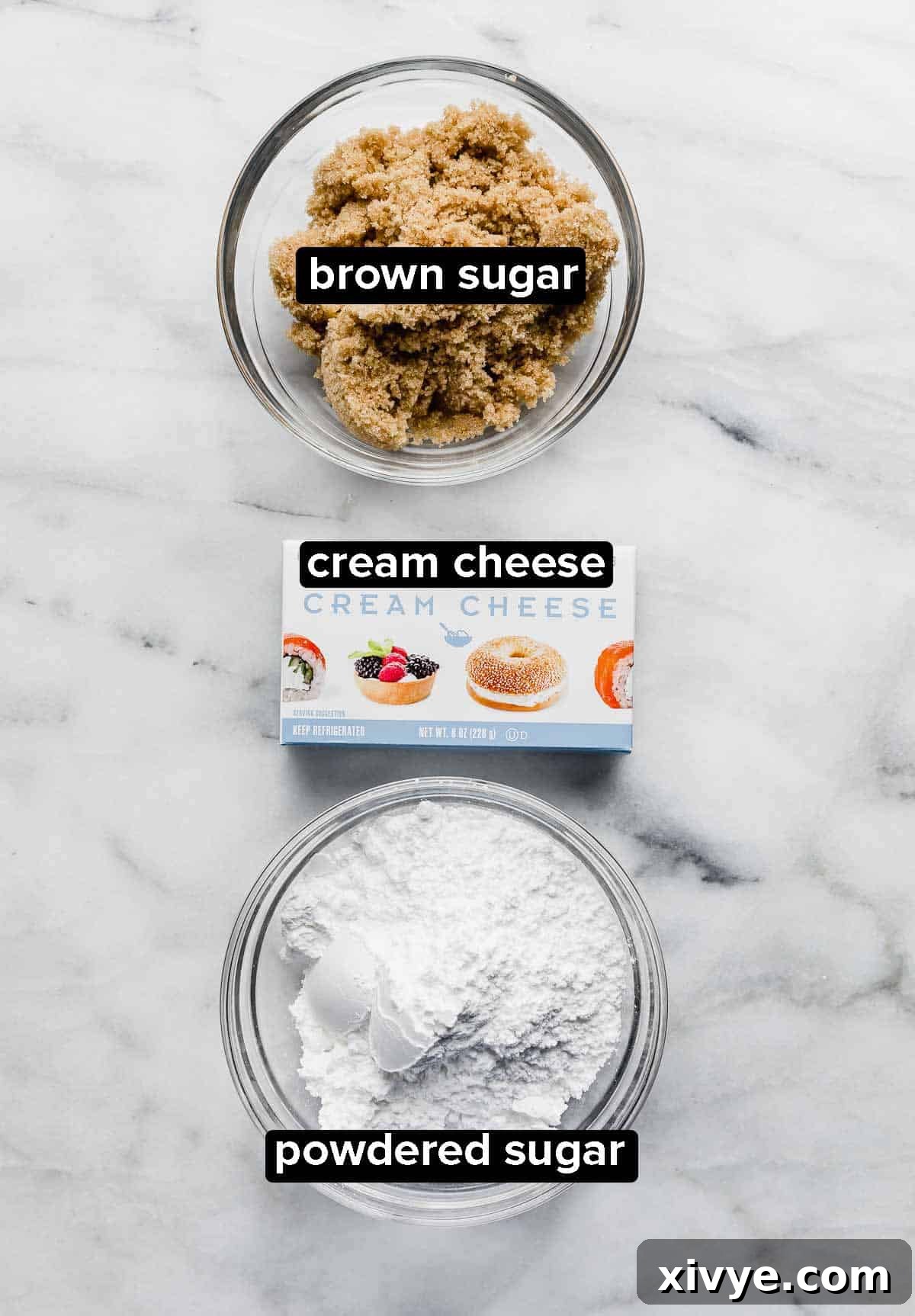 Three ingredients to make Cream Cheese Fruit Dip on a white background: brown sugar, cream cheese, and powdered sugar.