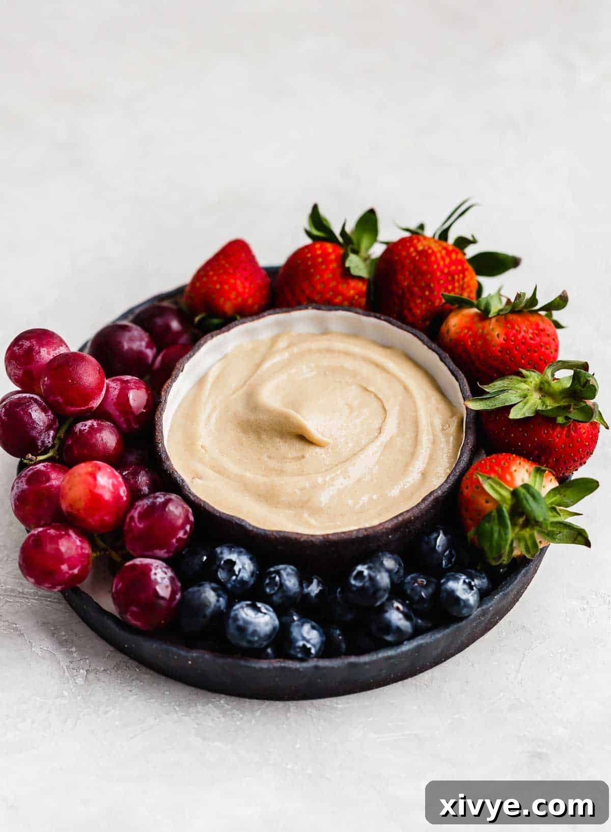 Three ingredient cream cheese fruit dip in a bowl on a light gray background.